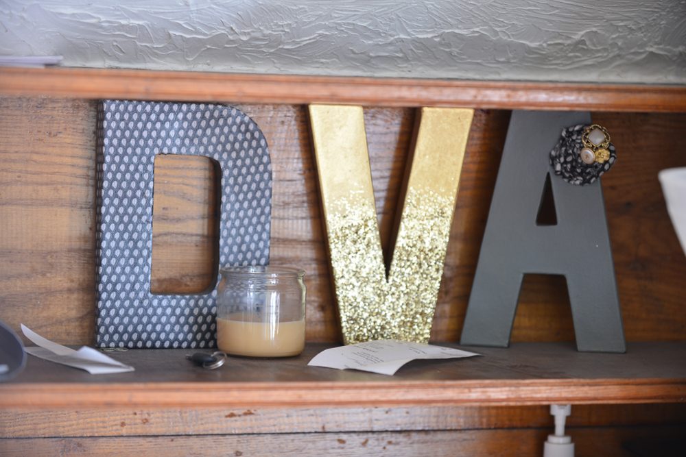 The gold D’Va letters on a reclaimed-wood sideboard